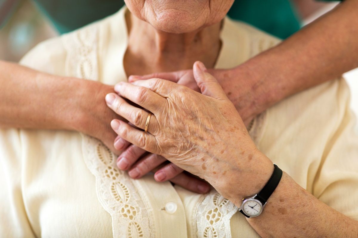 Nurse consoling her elderly patient by holding her hands